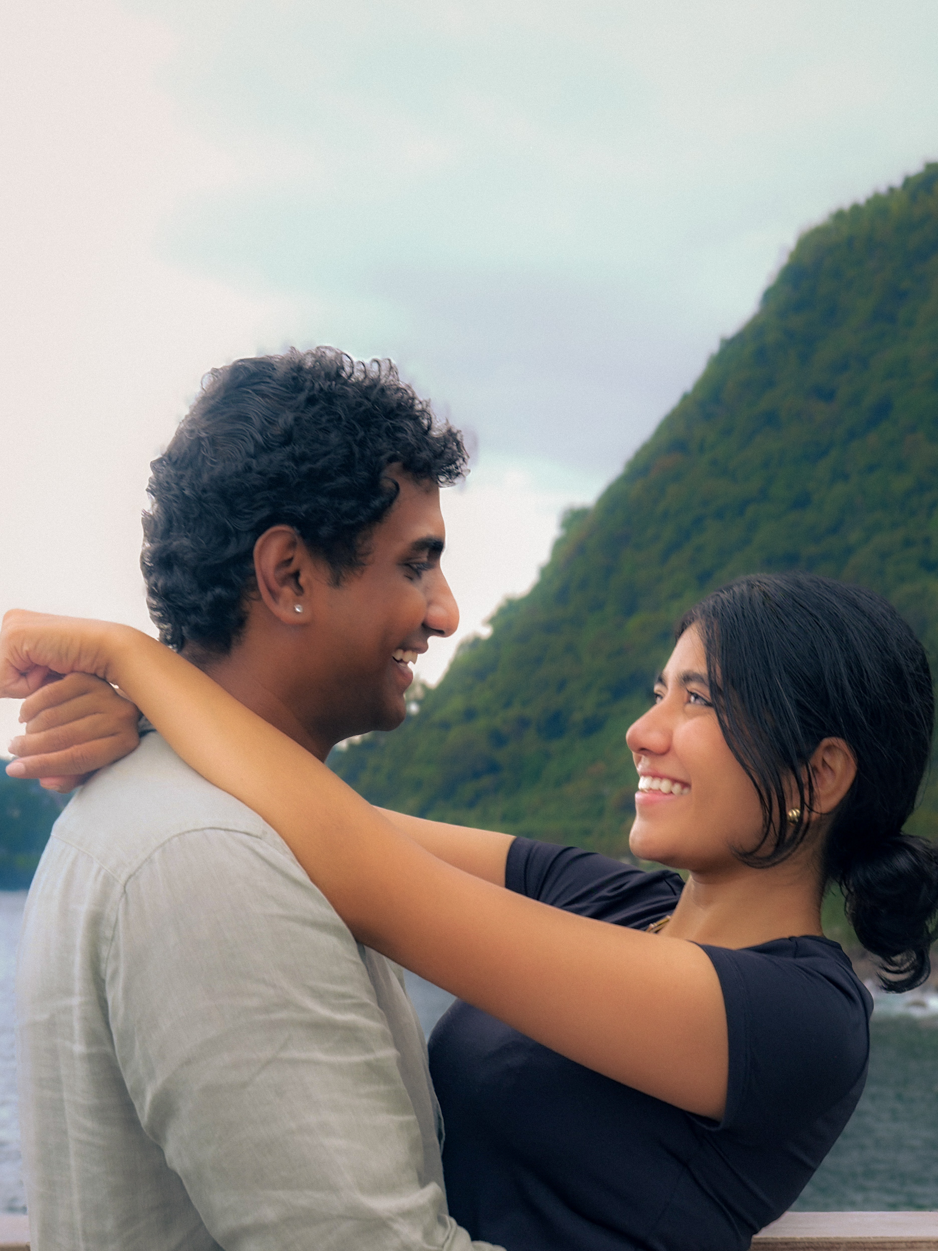 A close portrait of a couple embracing by the water.