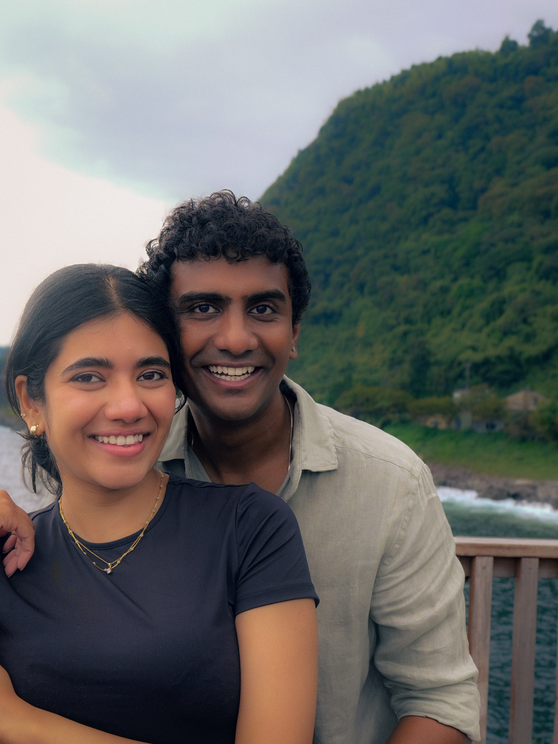 A smiling close portrait of the couple by the water.
