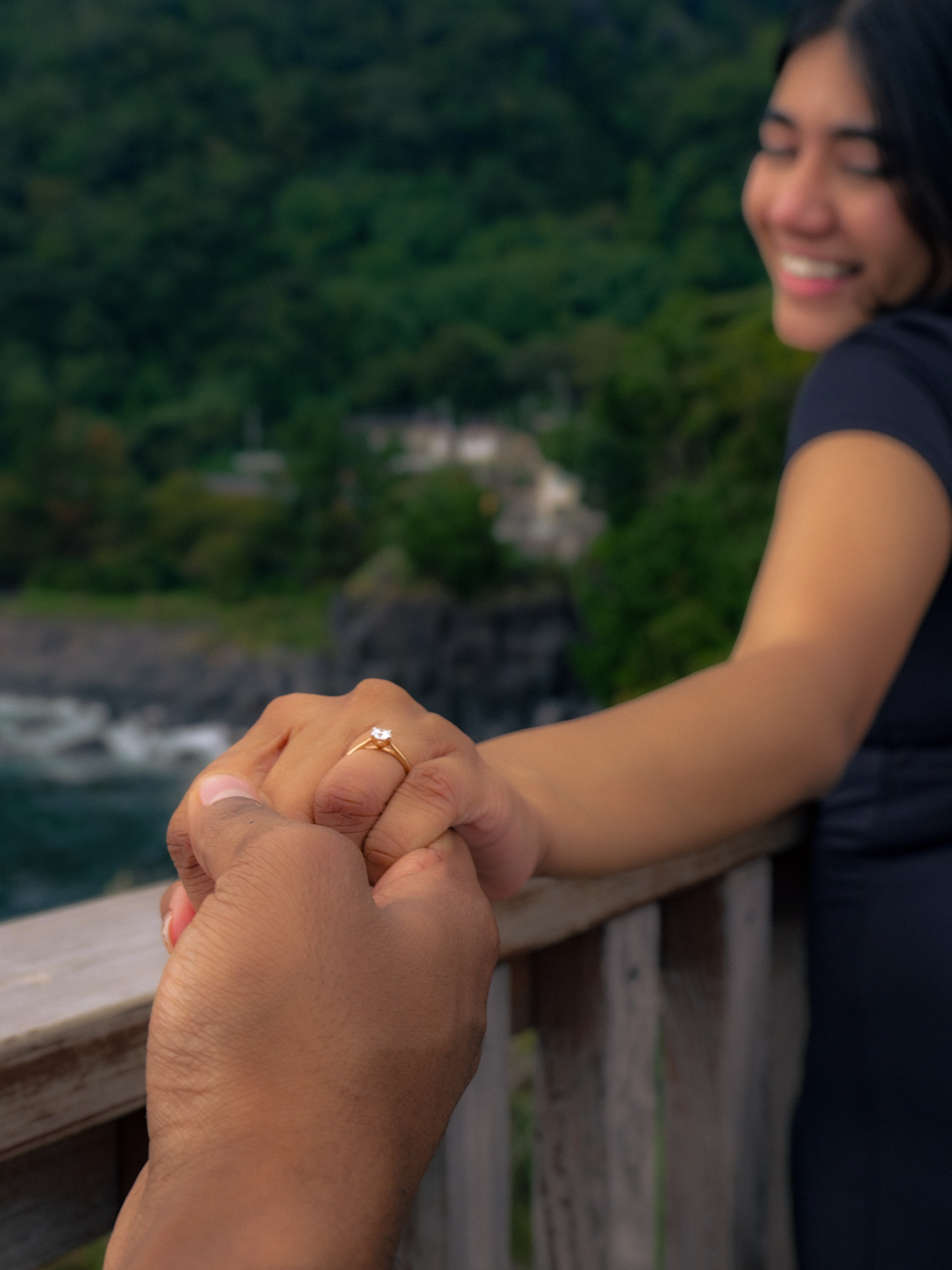 Hands intertwined with the engagement ring in focus.