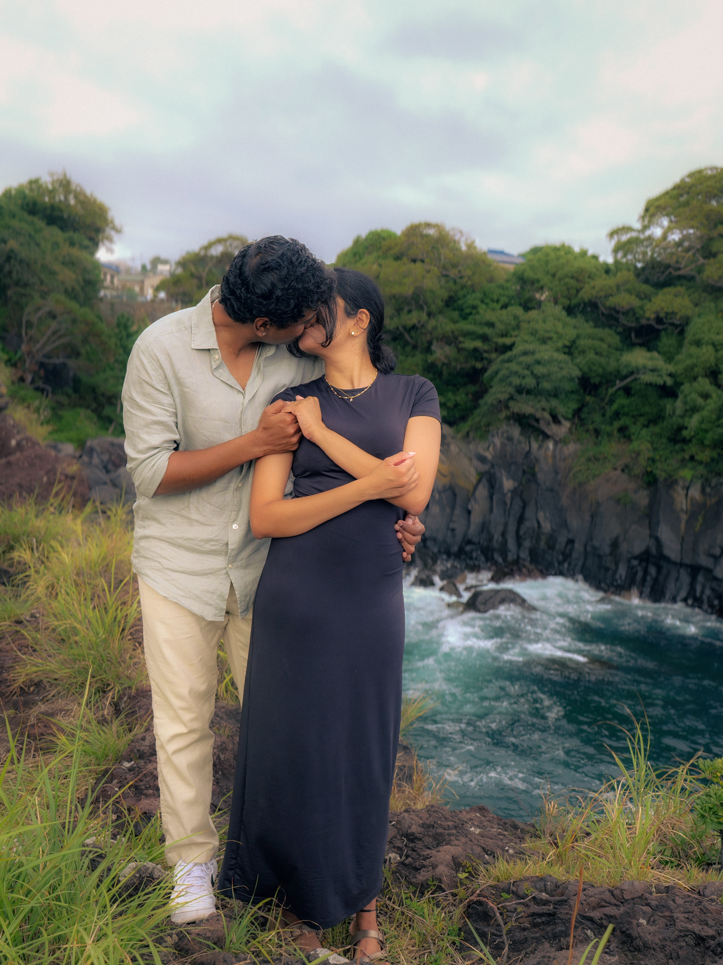 The couple kissing on the cliffside.